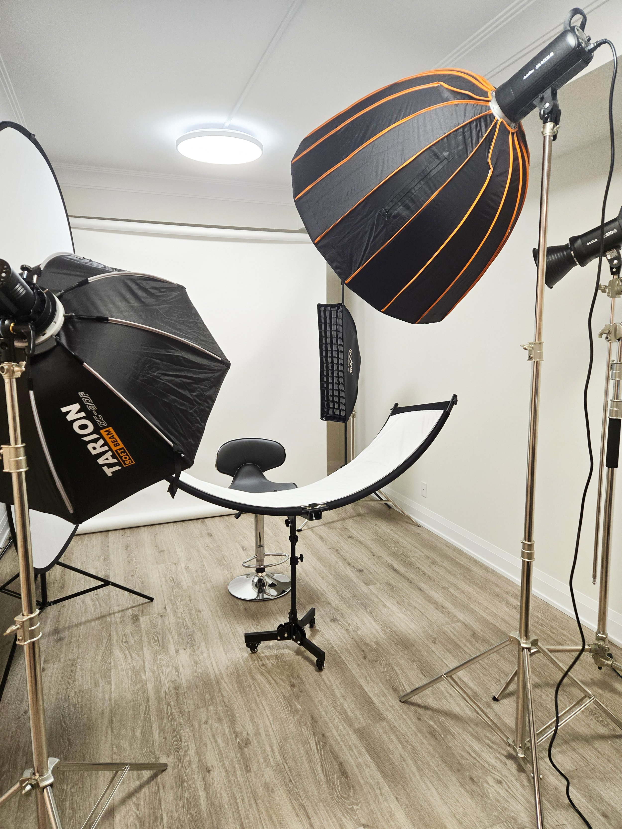 Toronto markham business photography studio with lighting setup including softboxes, a stool, a curved reflector on a stand, and a white backdrop. 多伦多职业照
